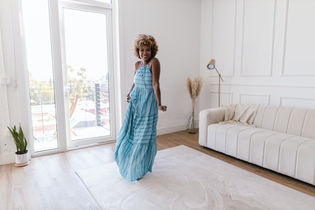 Woman in navy blue dress is dancing in a living room